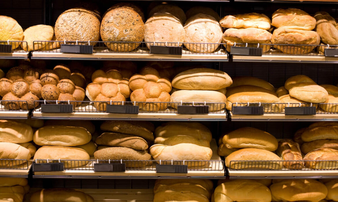 Estantería de panadería con bandejas llenas de panes variados